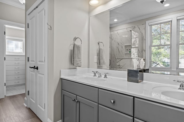 bathroom featuring hardwood / wood-style floors, crown molding, a tile shower, and vanity