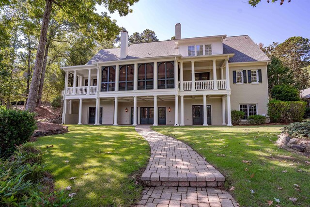 rear view of house featuring a yard and a balcony