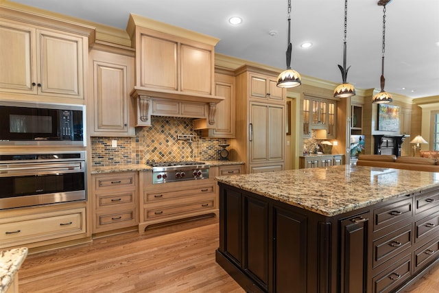 kitchen featuring pendant lighting, appliances with stainless steel finishes, dark brown cabinetry, tasteful backsplash, and light wood-type flooring