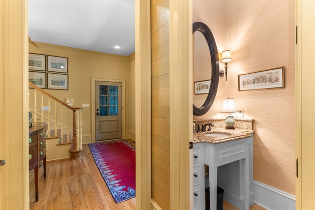 entrance foyer with crown molding, sink, and light hardwood / wood-style flooring