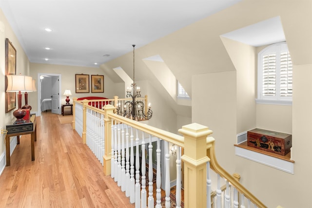 corridor with vaulted ceiling, light hardwood / wood-style floors, and a notable chandelier