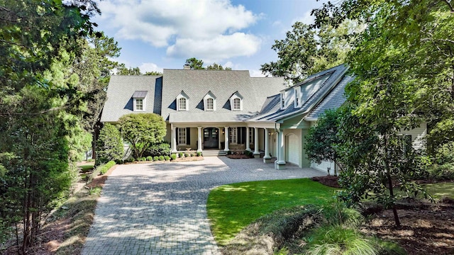 new england style home featuring a garage, a porch, and a front lawn