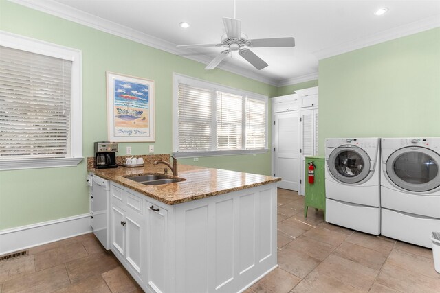 laundry area with crown molding, ceiling fan, sink, and washer and dryer