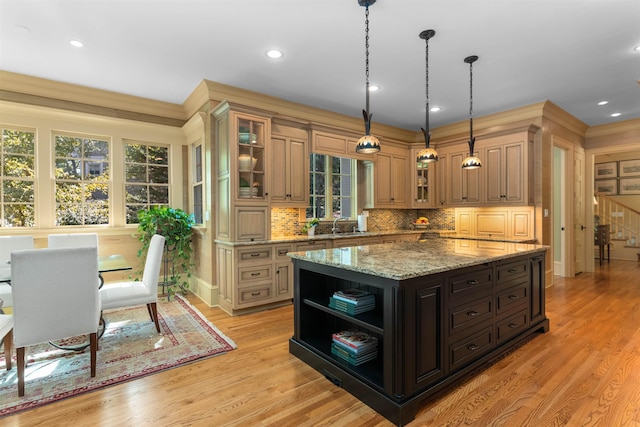 kitchen featuring backsplash, light hardwood / wood-style flooring, light stone countertops, and a kitchen island