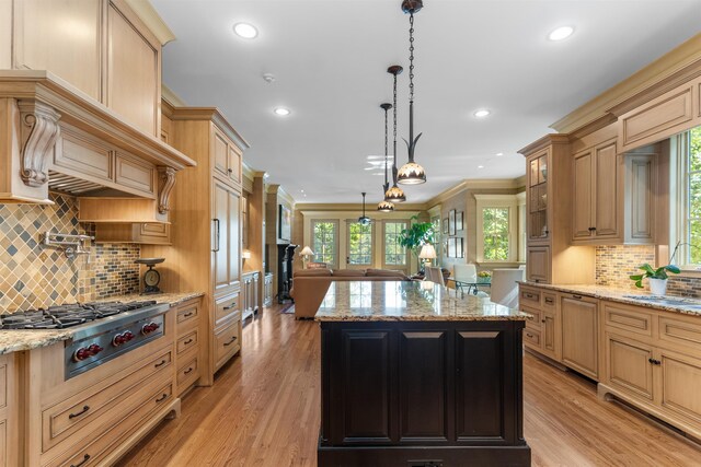 kitchen with light stone counters, decorative light fixtures, a center island, and stainless steel gas cooktop