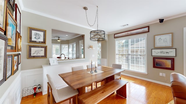 dining space with crown molding, a wealth of natural light, and light hardwood / wood-style floors