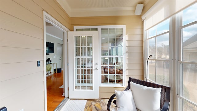 doorway to outside featuring wood-type flooring, ornamental molding, and wood walls