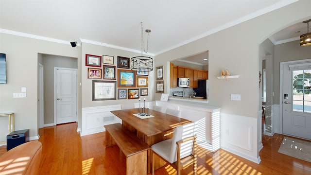 dining area with crown molding and light hardwood / wood-style floors