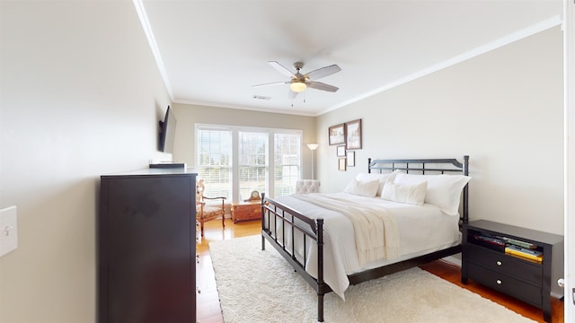 bedroom with crown molding, wood-type flooring, and ceiling fan