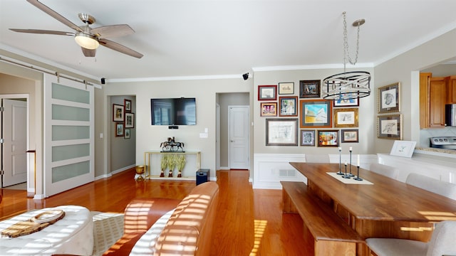 dining area featuring ornamental molding, a barn door, and light hardwood / wood-style flooring