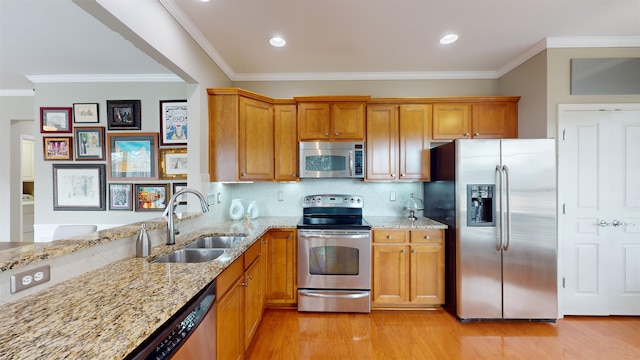 kitchen featuring sink, light wood-type flooring, light stone countertops, and appliances with stainless steel finishes