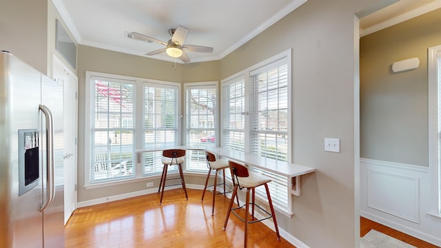 dining area with crown molding, ceiling fan, and light wood-type flooring