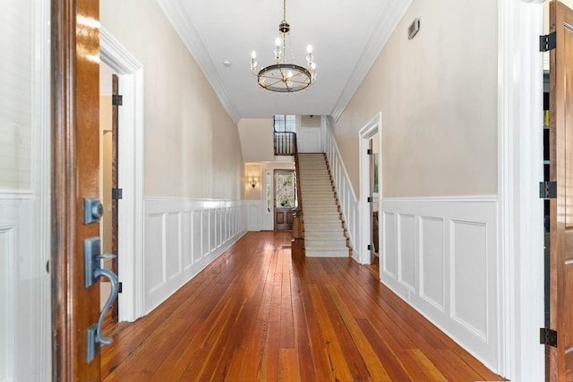 1011 Dogwood Dr, Greensboro, GA 30642 - corridor with crown molding, an inviting chandelier, a wainscoted wall, and hardwood / wood-style flooring
