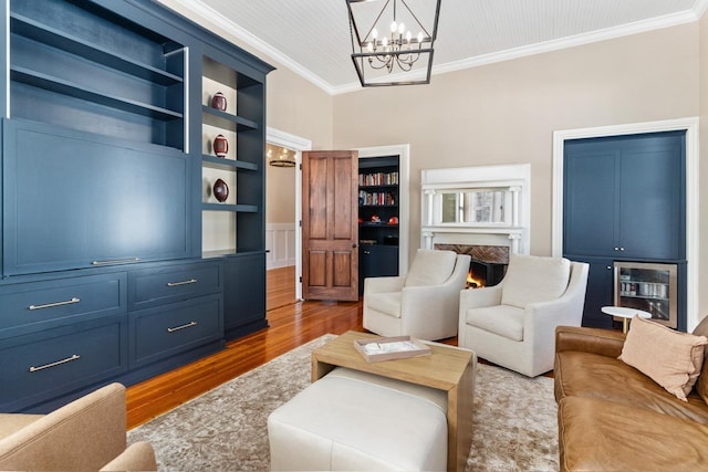 1011 Dogwood Dr, Greensboro, GA 30642 - living room with built in shelves, a warm lit fireplace, ornamental molding, a chandelier, and wood finished floors