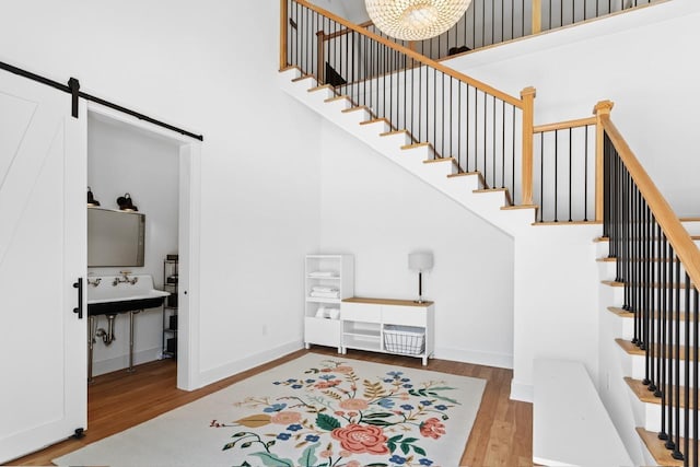 1011 Dogwood Dr, Greensboro, GA 30642 - stairs featuring baseboards, a barn door, a high ceiling, a chandelier, and wood finished floors