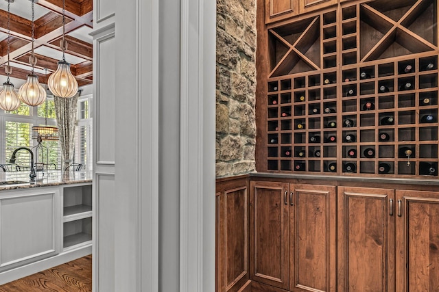 wine area featuring wood-type flooring, coffered ceiling, sink, and beam ceiling