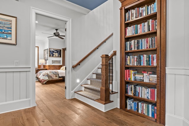 stairs with hardwood / wood-style floors, crown molding, and ceiling fan