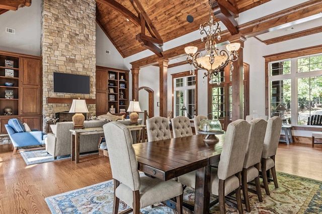 dining space with beam ceiling, wood ceiling, a fireplace, and light hardwood / wood-style floors