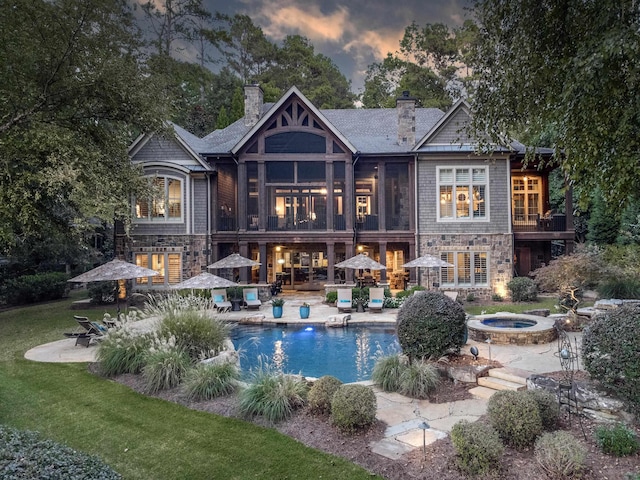 back house at dusk with a swimming pool with hot tub, a patio area, and an outdoor fire pit