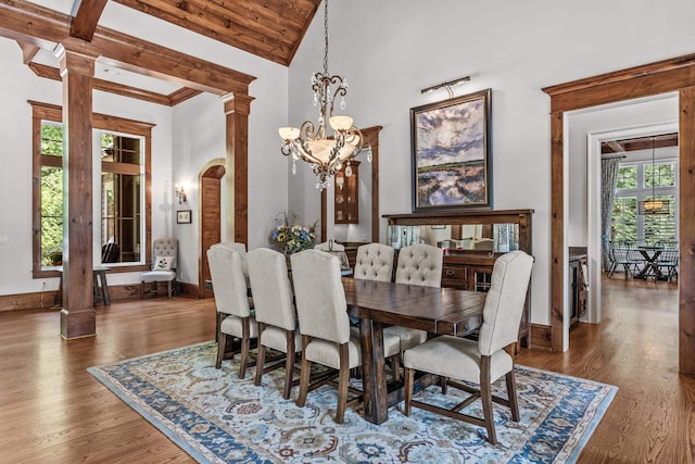 dining room featuring an inviting chandelier, dark hardwood / wood-style flooring, high vaulted ceiling, and ornate columns