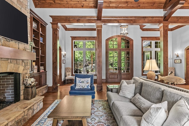 living room featuring ornate columns, a stone fireplace, dark hardwood / wood-style floors, beamed ceiling, and french doors