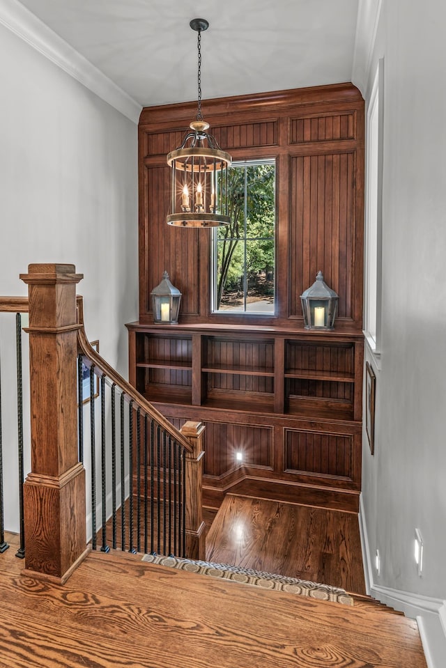 stairs featuring ornamental molding, hardwood / wood-style floors, and a notable chandelier