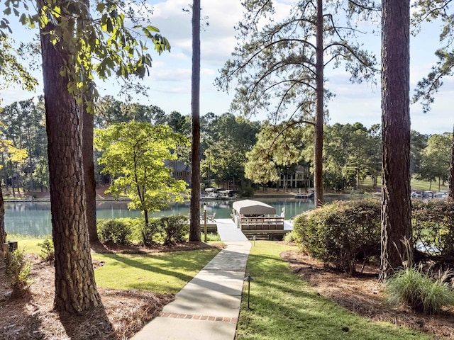 view of community with a water view, a yard, and a dock