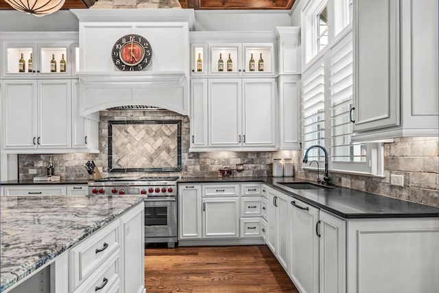 kitchen with sink, dark wood-type flooring, white cabinets, decorative backsplash, and designer stove