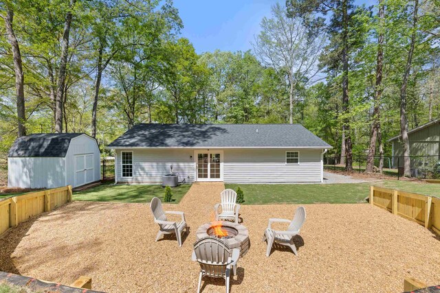 348 Bluegill Rd, Eatonton, GA 31024 - back of house with an outdoor structure, an outdoor fire pit, fence, a lawn, and a storage unit