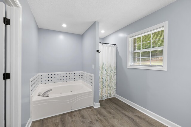 348 Bluegill Rd, Eatonton, GA 31024 - bathroom with a shower with shower curtain, baseboards, a textured ceiling, a garden tub, and wood finished floors