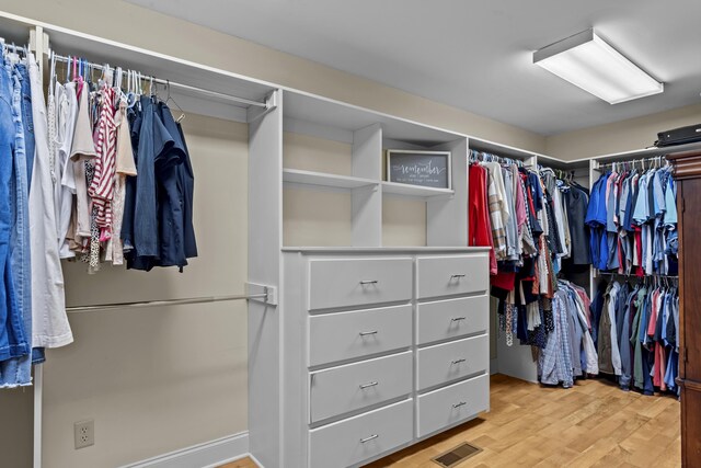 walk in closet with light hardwood / wood-style flooring