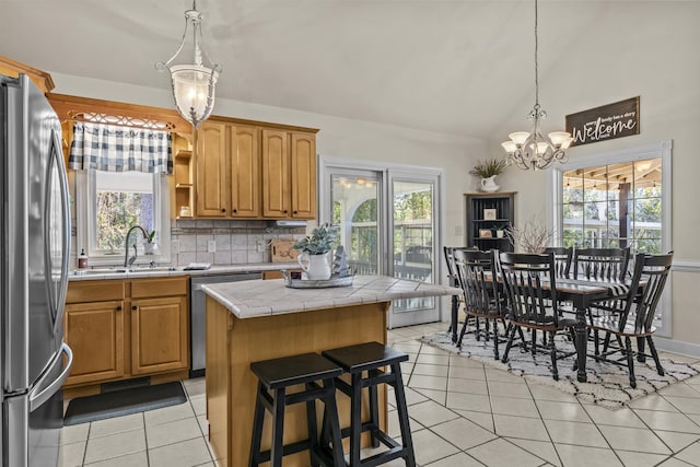 kitchen featuring sink, a center island, light tile patterned floors, appliances with stainless steel finishes, and tile counters