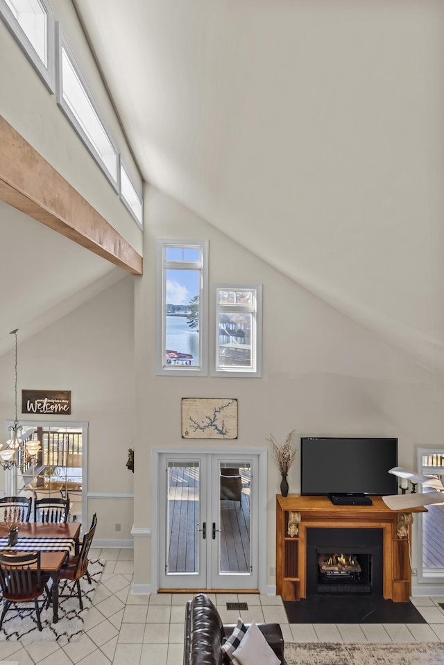 tiled living room with high vaulted ceiling, french doors, and a chandelier