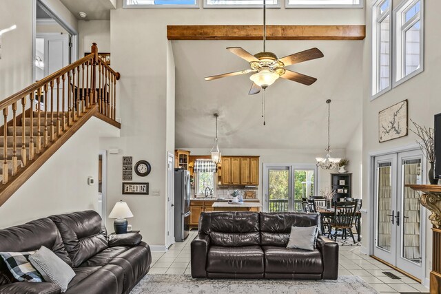 tiled living room with sink, a towering ceiling, and ceiling fan with notable chandelier