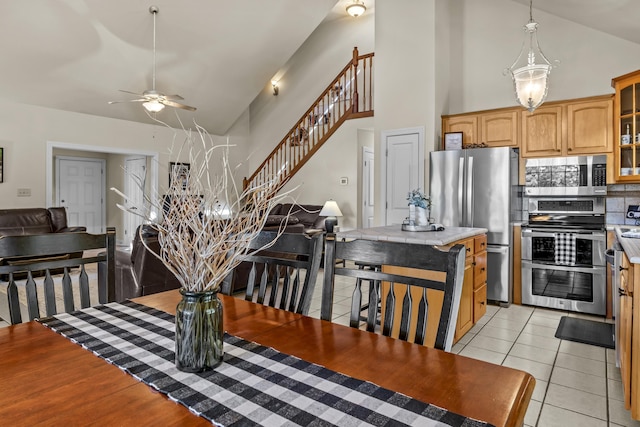 kitchen with ceiling fan, appliances with stainless steel finishes, high vaulted ceiling, light tile patterned flooring, and decorative backsplash