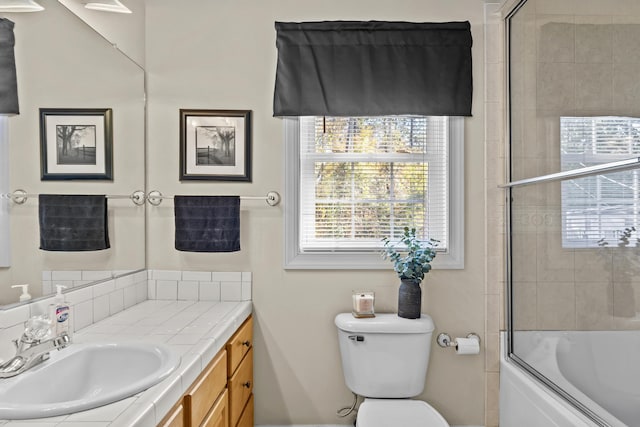 full bathroom featuring vanity, bath / shower combo with glass door, and toilet