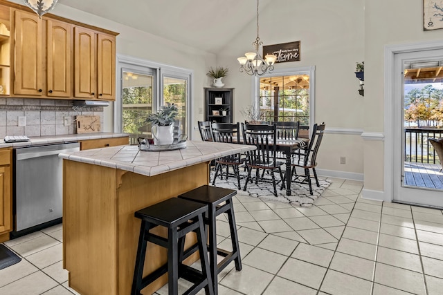 kitchen with a center island, a healthy amount of sunlight, dishwasher, and light tile patterned floors