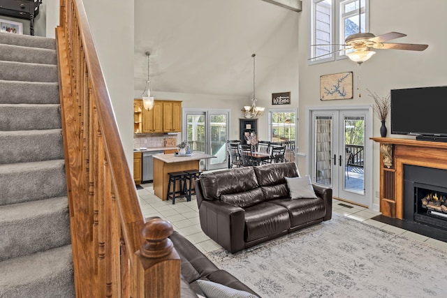 living room with light tile patterned flooring, ceiling fan with notable chandelier, french doors, and a high ceiling