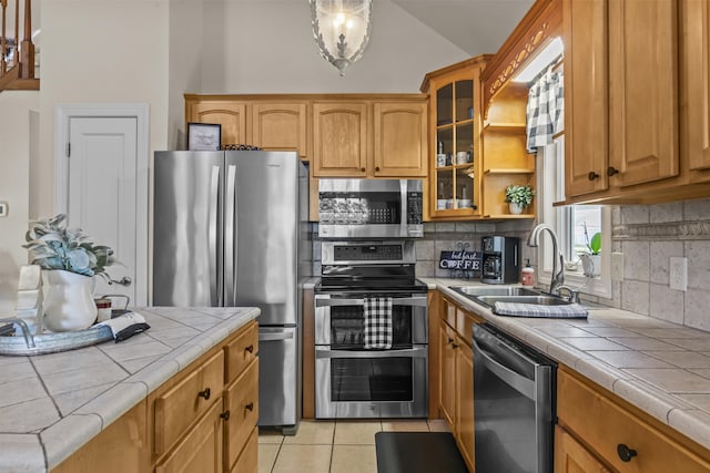 kitchen featuring appliances with stainless steel finishes, tile counters, sink, and light tile patterned floors