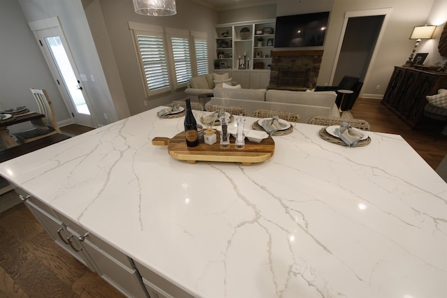 1060 Legend Dr, Greensboro, GA 30642 - kitchen with light stone countertops, a fireplace, dark wood-type flooring, built in features, and crown molding