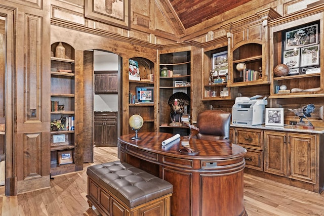 office space featuring vaulted ceiling, light wood-type flooring, and built in shelves