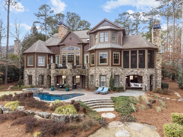 back of property with a sunroom, a pool with hot tub, and a patio