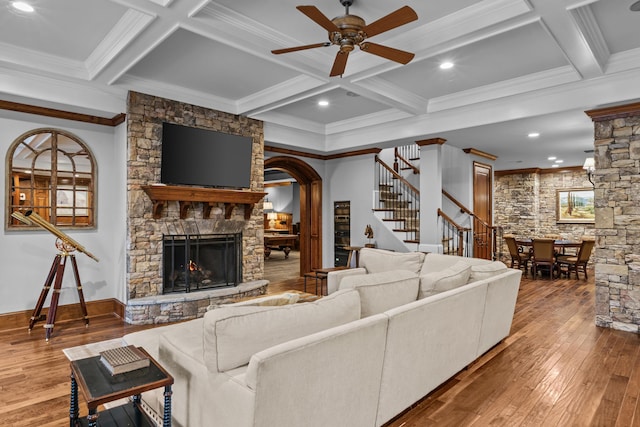 living room featuring hardwood / wood-style flooring, coffered ceiling, and a stone fireplace