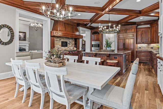 dining area featuring coffered ceiling, light hardwood / wood-style floors, beam ceiling, and a notable chandelier