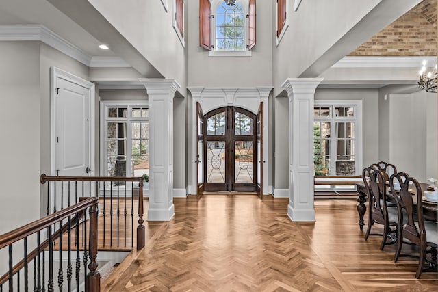 entrance foyer featuring parquet floors, crown molding, and ornate columns