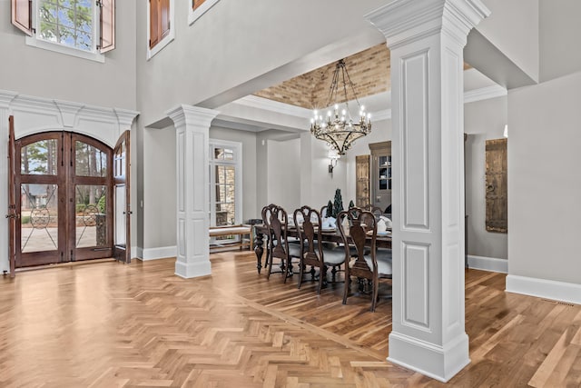 foyer featuring plenty of natural light, french doors, light parquet floors, and ornate columns