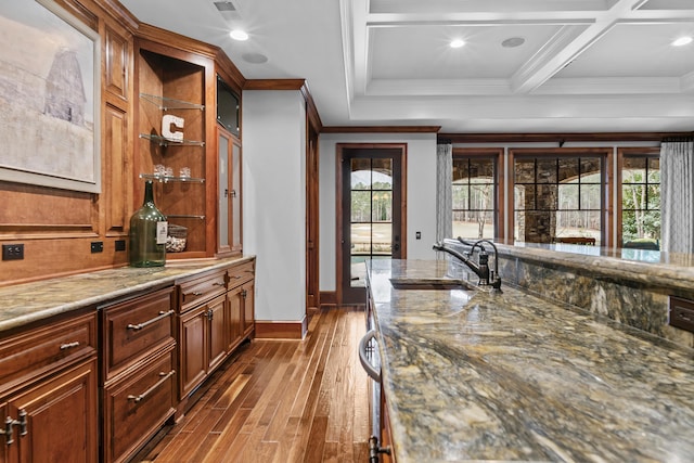 bar featuring coffered ceiling, sink, light stone counters, crown molding, and hardwood / wood-style floors