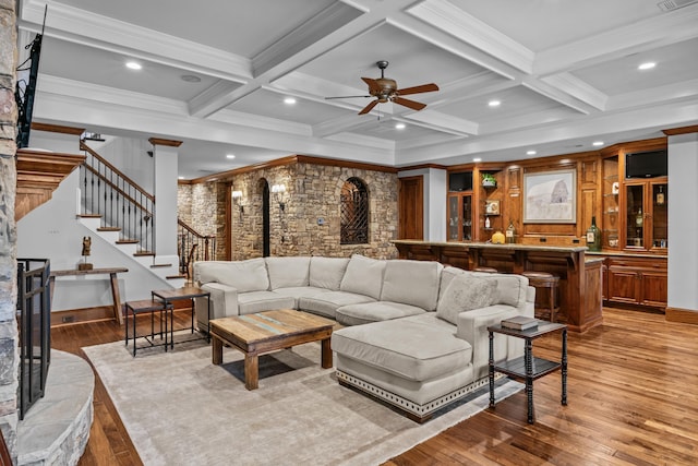 living room with coffered ceiling, beam ceiling, light hardwood / wood-style flooring, and ornamental molding