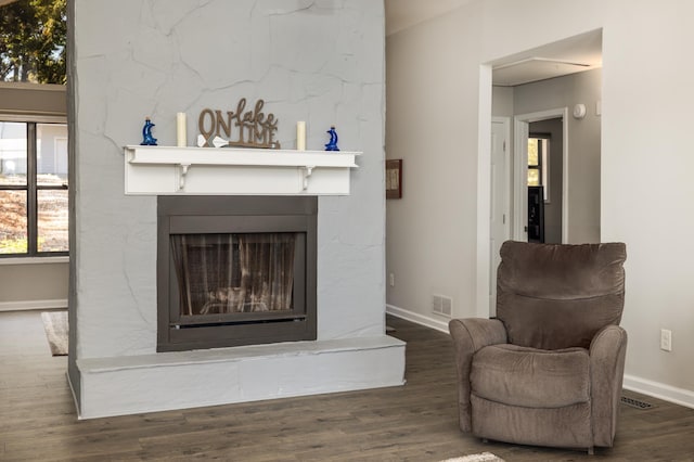 living area with a large fireplace and dark hardwood / wood-style flooring