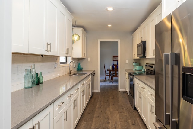 kitchen featuring sink, white cabinetry, appliances with stainless steel finishes, pendant lighting, and light stone countertops